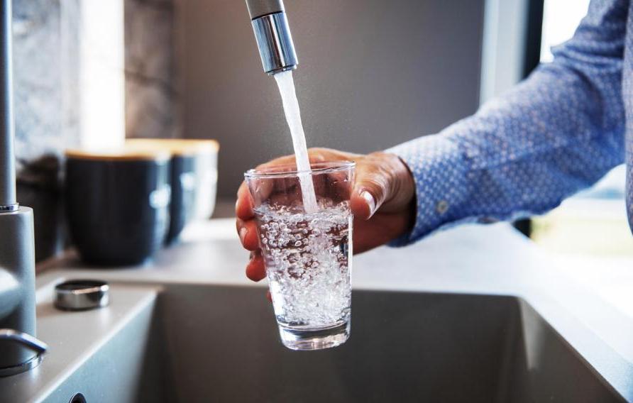 man filling glass of water from faucet